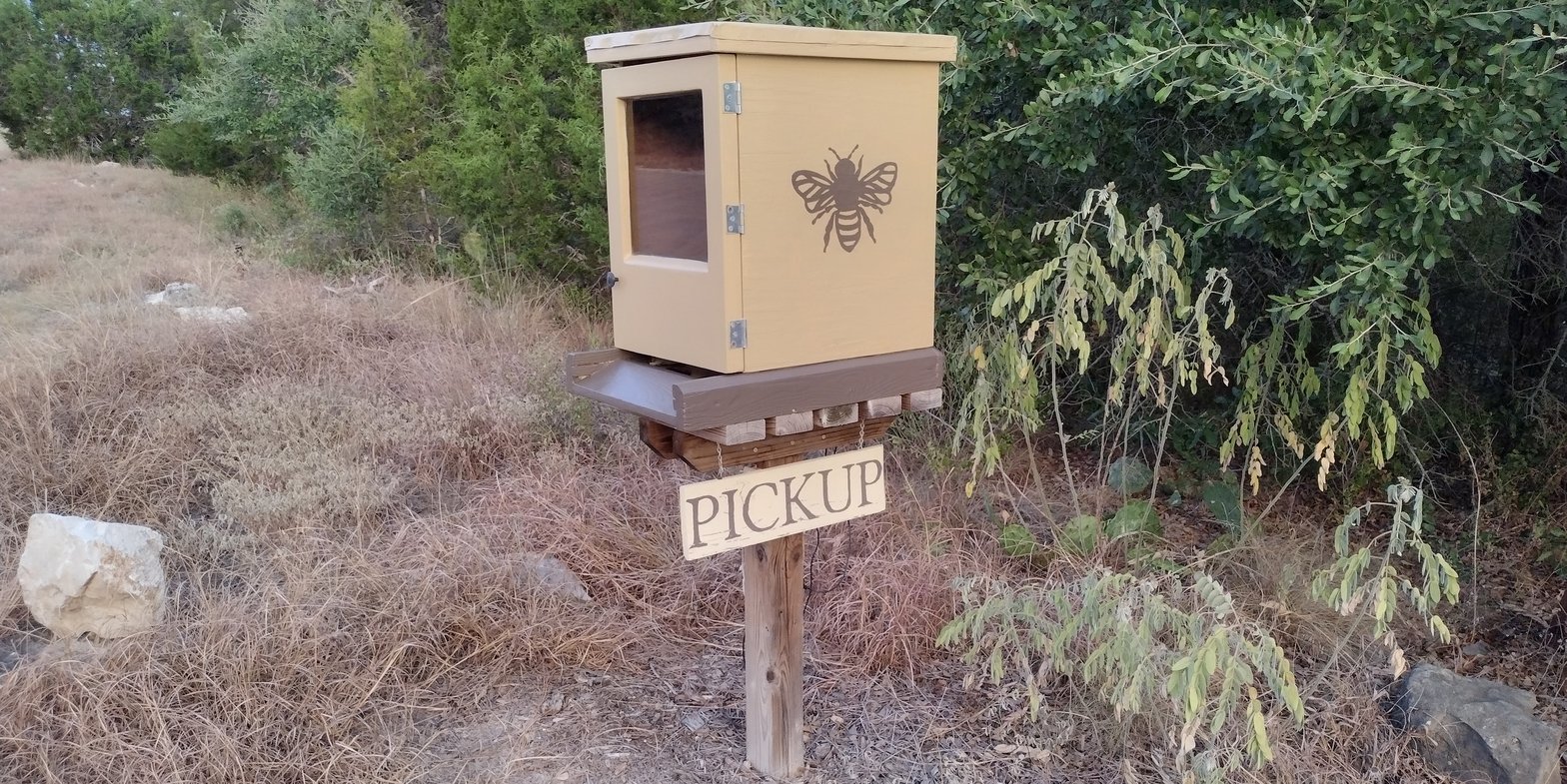 curbside pickup box located at dunsmore honey farm. A wooden box with bee on the side of it.